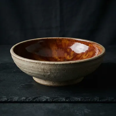 Stoneware serving bowl in sienna glaze, studio photograph