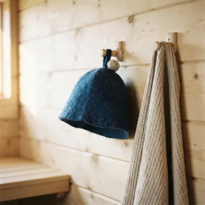 A blue bobble hat on a hook beside a towel