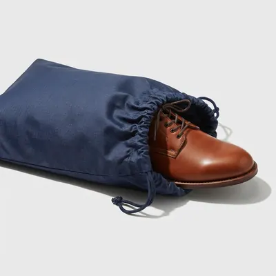 A navy shoe bag holding a leather shoe