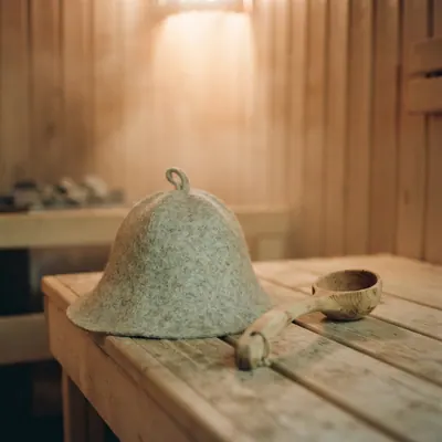 A wide brim felt hat on a sauna bench beside a ladle